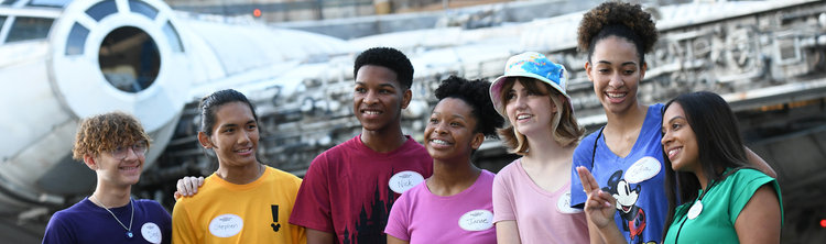 Group of people wearing name tags standing in front of a large sci‑fi spacecraft.