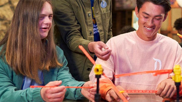 Disney Imagination Campus students sit around a table a they build a small scale of roller coaster