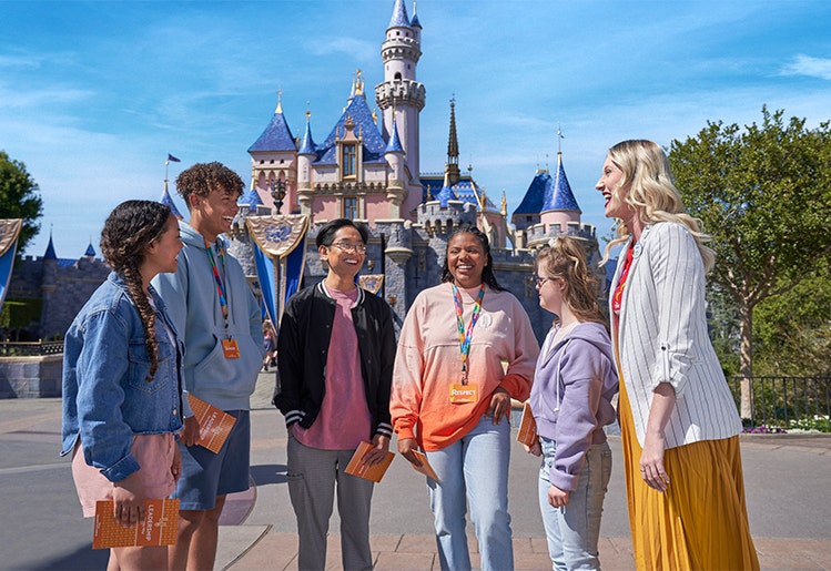 Students chatting with a Disney Cast Member near Sleeping Beauty Castle